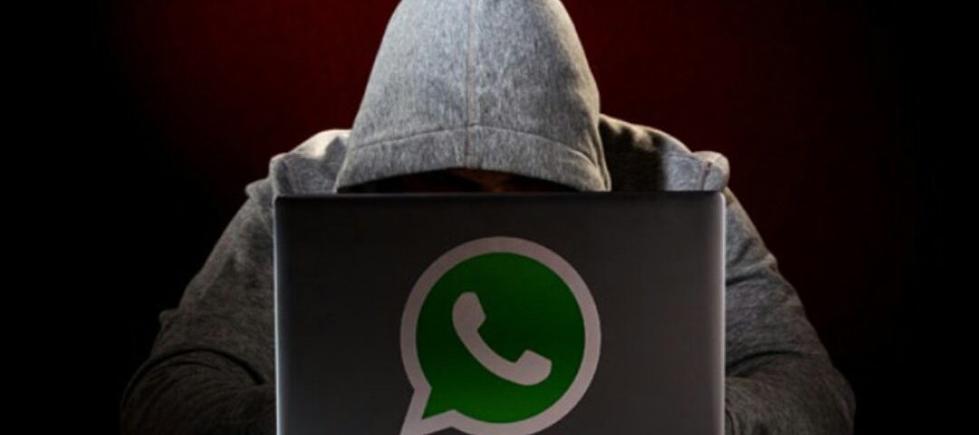 Foto de um hacker em seu notebook com a logo do WhatsApp