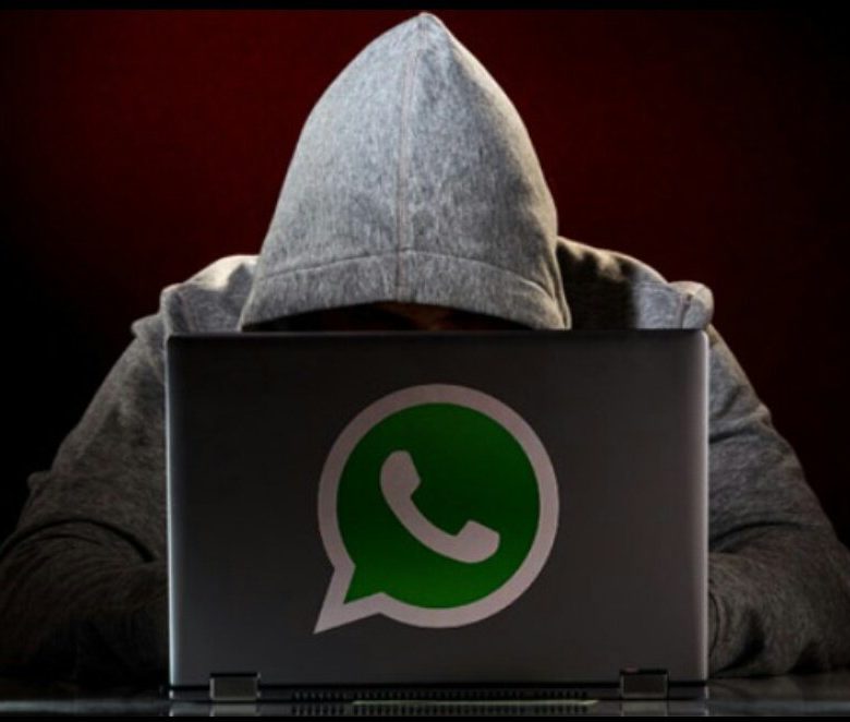 Foto de um hacker em seu notebook com a logo do WhatsApp